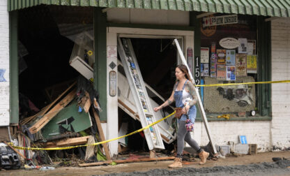 A person walks past a building heavily damaged during Hurricane Helene Tuesday, Oct. 1, 2024, in Hot Springs, N.C. (AP Photo/Jeff Roberson)