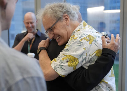 Victor Ambros, 2024 Nobel Prize winner in physiology or medicine, and professor of natural science at the University of Massachusetts Medical School, right, hugs collegue Allan Jacobson, at the school, in Worcester, Mass. Monday, Oct. 7, 2024. (AP Photo/Steven Senne)