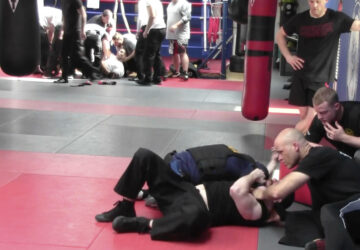 In this image from video made by the Evansville Police Department, rookie sheriff’s Deputy Asson Hacker, background left, lies unconscious after training with Mike Fisher, a sheriff's major from a nearby county, as another recruit undergoes training, foreground, during 