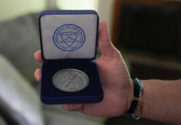 Lij Hacker holds a coin inscribed with the name of his late brother, Asson Hacker, during an interview in Bloomington, Ind., on June 4, 2024. (AP Photo/Darron Cummings)