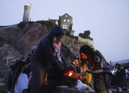 Gabby Flores, right, attempts to light charcoal as Kholoud Nasser helps block the wind on Indigenous Peoples Day on Monday, Oct. 14, 2024, in San Francisco. (AP Photo/Minh Connors)