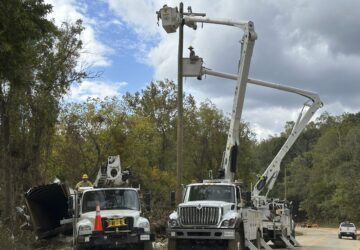 FILE - Contractors for Duke Energy rebuild destroyed electrical lines near the Swannanoa River in Asheville, N.C., Friday, Oct. 4, 2024. (AP Photo/Jeff Amy, File)