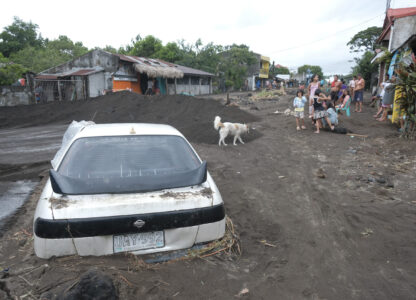 Residents stay beside a car partially buried by volcanic mud that had flowed down from Mayon volcano after heavy rains caused by Tropical Storm Trami hit Guinobatan town, Albay province, Philippines on Wednesday Oct. 23, 2024. (AP Photo/John Michael Magdasoc)