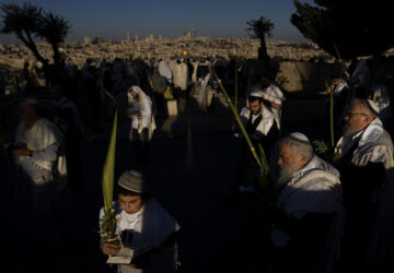 Ultra-Orthodox Jews wearing prayer shawls perform the Hoshana Rabbah prayer on the seventh day of the weeklong Jewish holiday of Sukkot at Mount of Olives overlooking Jerusalem's Old City with the Dome of the Rock shrine, Wednesday, Oct. 23, 2024. (AP Photo//Oded Balilty)