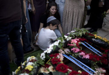 Relatives pause at the grave of Israel Defense Forces Captain Elad Siman Tov, who was killed in action in Lebanon, during his funeral in Petah Tikva, Israel, Friday, Oct. 18, 2024. (AP Photo/Maya Alleruzzo)