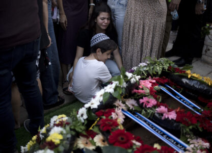 Relatives pause at the grave of Israel Defense Forces Captain Elad Siman Tov, who was killed in action in Lebanon, during his funeral in Petah Tikva, Israel, Friday, Oct. 18, 2024. (AP Photo/Maya Alleruzzo)