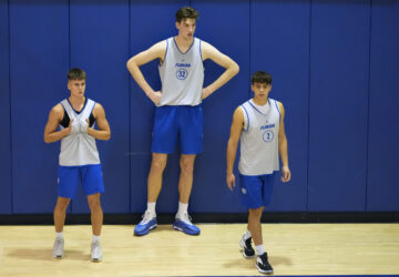 Olivier Rioux, center, a 7-foot-4 NCAA college basketball player from Florida, takes a break during practice with teammates Kajus Kublickas, left, and Kevin Pazmino (2), Friday, Oct. 18, 2024, in Gainesville, Florida. (AP Photo/John Raoux)