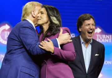 Former Democratic Rep. Tulsi Gabbard hugs Republican presidential nominee former President Donald Trump as Tucker Carlson yells during a campaign rally Wednesday, Oct. 23, 2024, in Duluth, Ga. (AP Photo/Alex Brandon)