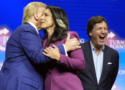 Former Democratic Rep. Tulsi Gabbard hugs Republican presidential nominee former President Donald Trump as Tucker Carlson yells during a campaign rally Wednesday, Oct. 23, 2024, in Duluth, Ga. (AP Photo/Alex Brandon)