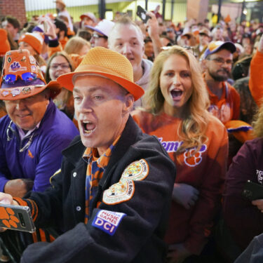 FILE - Clemson fans cheer on the Tigers as they arrive at Williams-Brice Stadium before an NCAA college football game against South Carolina Saturday, Nov. 27, 2021, in Columbia, S.C. (AP Photo/Sean Rayford, File)