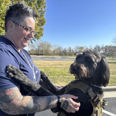 Air Force Staff Sgt. Heather O'Brien holds her labradoodle service dog, Albus, on Thursday, Nov. 7, 2024, in Kansas City, Kan. O'Brien is a part of Dogs 4 Valor that helps retired veterans and first responders in the Kansas City area work with their service dogs to help manage depression, anxiety and other challenges. (AP Photo/Nick Ingram)