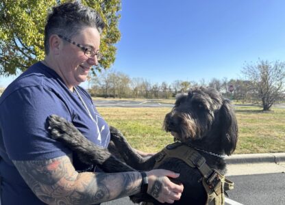 Air Force Staff Sgt. Heather O'Brien holds her labradoodle service dog, Albus, on Thursday, Nov. 7, 2024, in Kansas City, Kan. O'Brien is a part of Dogs 4 Valor that helps retired veterans and first responders in the Kansas City area work with their service dogs to help manage depression, anxiety and other challenges. (AP Photo/Nick Ingram)