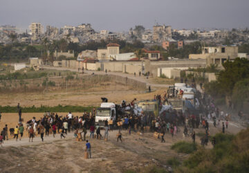 FILE - Palestinians are storming trucks loaded with humanitarian aid brought in through a new U.S.-built pier, in the central Gaza Strip, on May 18, 2024. (AP Photo/Abdel Kareem Hana, File)