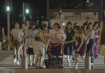 In this photo taken Sept. 8, 2023, attendees cross the road with DJ equipment on a cart during a public party organized by Loong Wu through streets of Shenzhen in southern China's Guangdong province. (Wu Peicheng via AP)