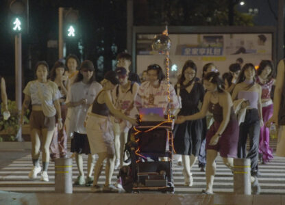 In this photo taken Sept. 8, 2023, attendees cross the road with DJ equipment on a cart during a public party organized by Loong Wu through streets of Shenzhen in southern China's Guangdong province. (Wu Peicheng via AP)