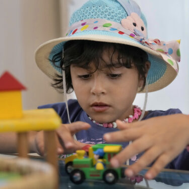 Palestinian girl Halima Abou Yassine, 7, who was brought to Lebanon from Gaza Strip for treatment after an Israeli strike left her near death with a gaping wound in her skull, plays with a toy car at a summer camp in Beirut, Lebanon, Friday, Aug. 30, 2024. (AP Photo/Bilal Hussein)