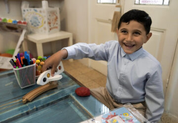 Palestinian Adam Afana, 5, who was brought to Lebanon from Gaza Strip for treatment who had nearly lost his left arm in an Israeli airstrike that killed his father and sister, plays with a toy plane at a summer camp in Beirut, Lebanon, Friday, Aug. 30, 2024. (AP Photo/Bilal Hussein)