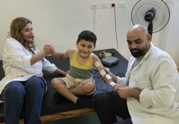 Adam Afana, 5, center, who was brought to Lebanon from the Gaza Strip for treatment after he nearly lost his left arm in an Israeli airstrike that killed his father and sister, receives physiotherapy at a clinic in Mar Elias Palestinian refugee camp in Beirut, Lebanon, Wednesday, Sept. 4, 2024. (AP Photo/Bilal Hussein)