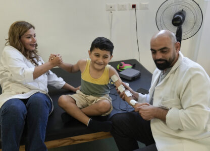 Adam Afana, 5, center, who was brought to Lebanon from the Gaza Strip for treatment after he nearly lost his left arm in an Israeli airstrike that killed his father and sister, receives physiotherapy at a clinic in Mar Elias Palestinian refugee camp in Beirut, Lebanon, Wednesday, Sept. 4, 2024. (AP Photo/Bilal Hussein)