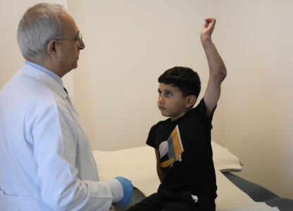 Orthopedic and spine surgeon Dr. Rachid Haidar, left, checks Adam Afana, 5, who was brought to Lebanon from Gaza for treatment after nearly losing his left arm in an Israeli airstrike that killed his father and sister, as his uncle, Eid Afana, right, stands next to him at the American University of Beirut Medical Center, in Beirut, Lebanon, Monday, July 15, 2024. (AP Photo/Hussein Malla)