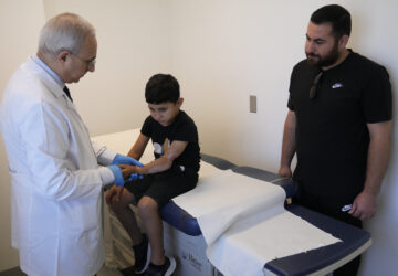 Orthopedic and spine surgeon Dr. Rachid Haidar, left, checks the arm of a Palestinian boy, Adam Afana, 5, who was brought to Lebanon from Gaza for treatment after nearly losing his left arm in an Israeli airstrike that killed his father and sister, at the American University of Beirut Medical Center, in Beirut, Lebanon, Monday, July 15, 2024. (AP Photo/Hussein Malla)