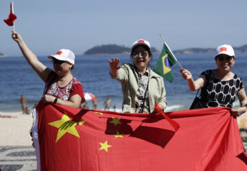 People wave Chinese and Brazilian flags as they wait for China's President Xi Jinping for him to drive past Leblon beach to his hotel during the G20 summit in Rio de Janeiro, Monday, Nov. 18, 2024. (AP Photo/Bruna Prado)