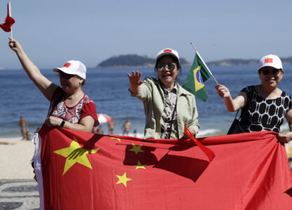 People wave Chinese and Brazilian flags as they wait for China's President Xi Jinping for him to drive past Leblon beach to his hotel during the G20 summit in Rio de Janeiro, Monday, Nov. 18, 2024. (AP Photo/Bruna Prado)