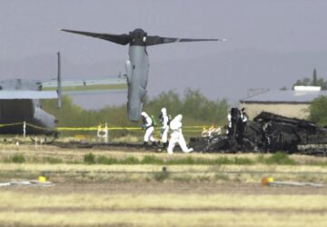 FILE - White suited workers investigate the crash scene of a Marine Corps MV-22 Osprey at the Avra Valley Airport, north of Tucson, Ariz., April 9, 2000. A Marine Corps aircraft attempting to land during a nighttime training mission crashed and burst into flames, killing all 19 aboard and adding to a checkered history for a new breed of hybrid plane that can take off and land like a helicopter. (AP Photo/Jon Hayt, File)