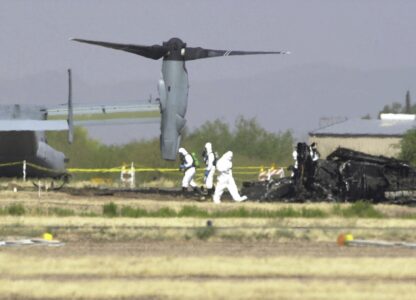 FILE - White suited workers investigate the crash scene of a Marine Corps MV-22 Osprey at the Avra Valley Airport, north of Tucson, Ariz., April 9, 2000. A Marine Corps aircraft attempting to land during a nighttime training mission crashed and burst into flames, killing all 19 aboard and adding to a checkered history for a new breed of hybrid plane that can take off and land like a helicopter. (AP Photo/Jon Hayt, File)