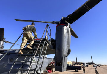 Master Sgt. Frank Williams, the production superintendent of the 20th Special Operations aircraft maintenance squadron at Cannon Air Force Base, N.M., climbs a ladder to show where hydraulic lines at the joint of the rotating engine and transmission need to be checked on the Osprey after flights, Oct. 8, 2024. (AP Photo/Tara Copp)