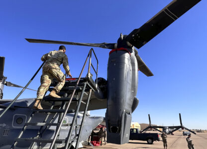 Master Sgt. Frank Williams, the production superintendent of the 20th Special Operations aircraft maintenance squadron at Cannon Air Force Base, N.M., climbs a ladder to show where hydraulic lines at the joint of the rotating engine and transmission need to be checked on the Osprey after flights, Oct. 8, 2024. (AP Photo/Tara Copp)