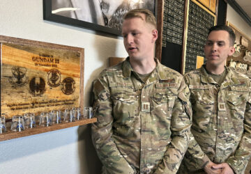 Osprey pilots Capt. Christian Eells, left, and Capt. Matthew Gulotta stand Oct. 8, 2024, at Cannon Air Force Base, N.M., beside a memorial to the Air Force Special Operations Command Osprey callsign 