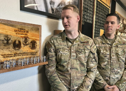 Osprey pilots Capt. Christian Eells, left, and Capt. Matthew Gulotta stand Oct. 8, 2024, at Cannon Air Force Base, N.M., beside a memorial to the Air Force Special Operations Command Osprey callsign 