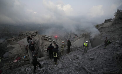 FILE - Rescue workers and people gather on the rubble of a house hit in an Israeli airstrike in Baalchmay village east of Beirut, Lebanon, on Nov. 12, 2024. (AP Photo/Hassan Ammar, File)