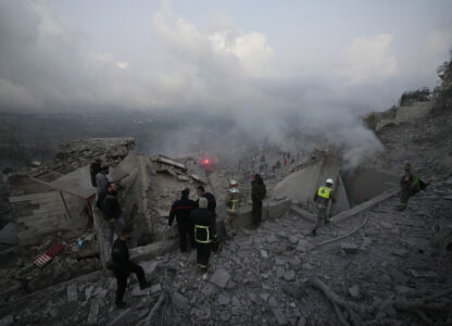 FILE - Rescue workers and people gather on the rubble of a house hit in an Israeli airstrike in Baalchmay village east of Beirut, Lebanon, on Nov. 12, 2024. (AP Photo/Hassan Ammar, File)