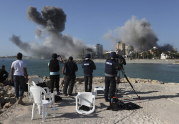 FILE - Journalists film as smoke rises from buildings hit in Israeli airstrikes in Tyre, southern Lebanon, on Oct. 28, 2024. (AP Photo/Mohammed Zaatari, File)