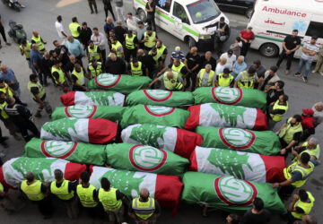 FILE - Paramedics stand next to the coffins of people who were killed in an Israeli airstrike in Barja, during their funeral procession in Tyre, southern Lebanon, on Nov. 7, 2024. (AP Photo/Mohammed Zaatari, File)