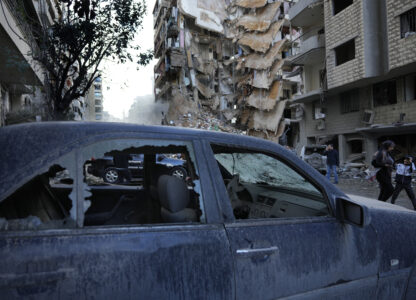 Residents pass in front of a destroyed building that was hit Sunday night in an Israeli airstrike in Dahiyeh, in the southern suburb of Beirut, Lebanon, Monday, Nov. 25, 2024. (AP Photo/Hussein Malla)