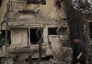 A man walks past a damaged building after a rocket fired from Lebanon hit an area in Rinatya, outskirts of Tel Aviv, Israel, Sunday, Nov. 24, 2024. (AP Photo/Leo Correa)