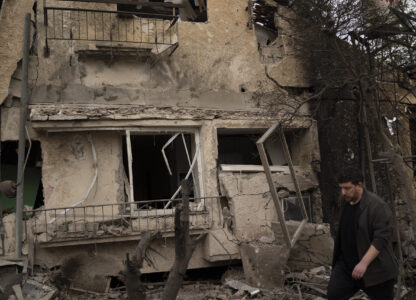 A man walks past a damaged building after a rocket fired from Lebanon hit an area in Rinatya, outskirts of Tel Aviv, Israel, Sunday, Nov. 24, 2024. (AP Photo/Leo Correa)