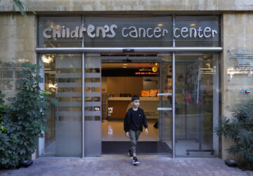 Mohammad Mousawi, 8, a displaced boy from the southern suburb of Beirut who suffers from leukaemia, steps out the entrance of the Children's Cancer Center of Lebanon, in Beirut, Lebanon, Friday, Nov. 15, 2024. (AP Photo/Hussein Malla)