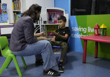 Mohammad Mousawi, 8, a displaced boy from the southern suburb of Beirut who suffers from leukaemia, attends with a volunteer who offers him a compassionate care and entertainment ahead of his weekly treatment at the Children's Cancer Center of Lebanon, in Beirut, Lebanon, Friday, Nov. 15, 2024. (AP Photo/Hussein Malla)