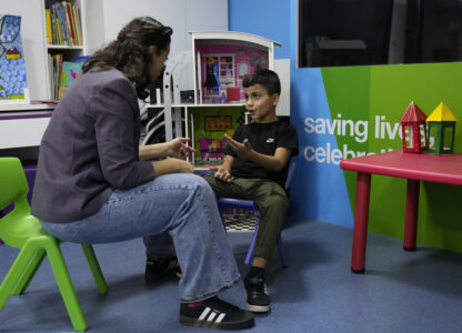 Mohammad Mousawi, 8, a displaced boy from the southern suburb of Beirut who suffers from leukaemia, attends with a volunteer who offers him a compassionate care and entertainment ahead of his weekly treatment at the Children's Cancer Center of Lebanon, in Beirut, Lebanon, Friday, Nov. 15, 2024. (AP Photo/Hussein Malla)