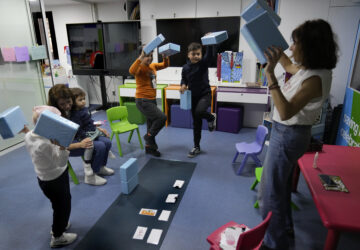 Children who suffers from cancer, enjoy at a playroom with a volunteer ahead of their treatments at the Children's Cancer Center of Lebanon, in Beirut, Lebanon, Friday, Nov. 15, 2024. (AP Photo/Hussein Malla)