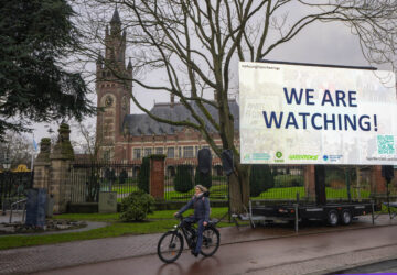 Activists put up a billboard outside the International Court of Justice, in The Hague, Netherlands, as it opens hearings into what countries worldwide are legally required to do to combat climate change and help vulnerable nations fight its devastating impact, Monday, Dec. 2, 2024. (AP Photo/Peter Dejong)