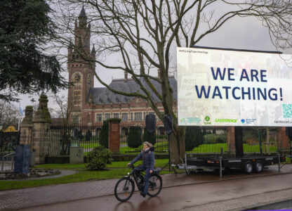 Activists put up a billboard outside the International Court of Justice, in The Hague, Netherlands, as it opens hearings into what countries worldwide are legally required to do to combat climate change and help vulnerable nations fight its devastating impact, Monday, Dec. 2, 2024. (AP Photo/Peter Dejong)