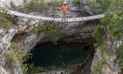 A man looks down from a bridge into the Santa Cruz cenote in Homun, Mexico, Tuesday, March 5, 2024. (AP Photo/Rodrigo Abd)