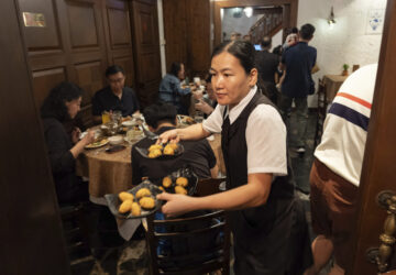 A waitress serves orders of cod fish cakes during lunch hour at a family-run Restaurante Litoral in Macao, on Nov. 11, 2024. (AP Photo/Anthony Kwan)