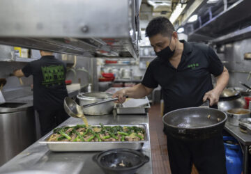 A staff member pours sauce onto a traditional local casserole called Tacho, made up of chicken, Chinese-style air dried pork sausages and local vegetables, at the family-run Restaurante Litoral in Macao, on Nov. 11, 2024. (AP Photo/Anthony Kwan)