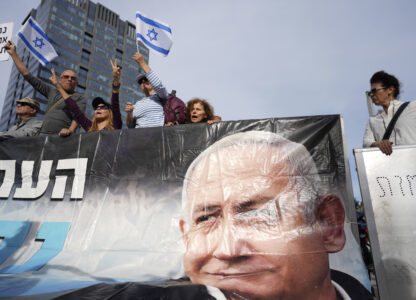 Supporters of Israel's Prime Minster Benjamin Netanyahu, seen in poster, gather outside a court in Tel Aviv, Israel, Tuesday, Dec. 10, 2024 as Netanyahu is set to take the stand in his long-running trial on corruption charges. (AP Photo/Ariel Schalit)